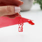 LOVE red acrylic laser cut earrings shown being held by a hand to see the drop of the earring