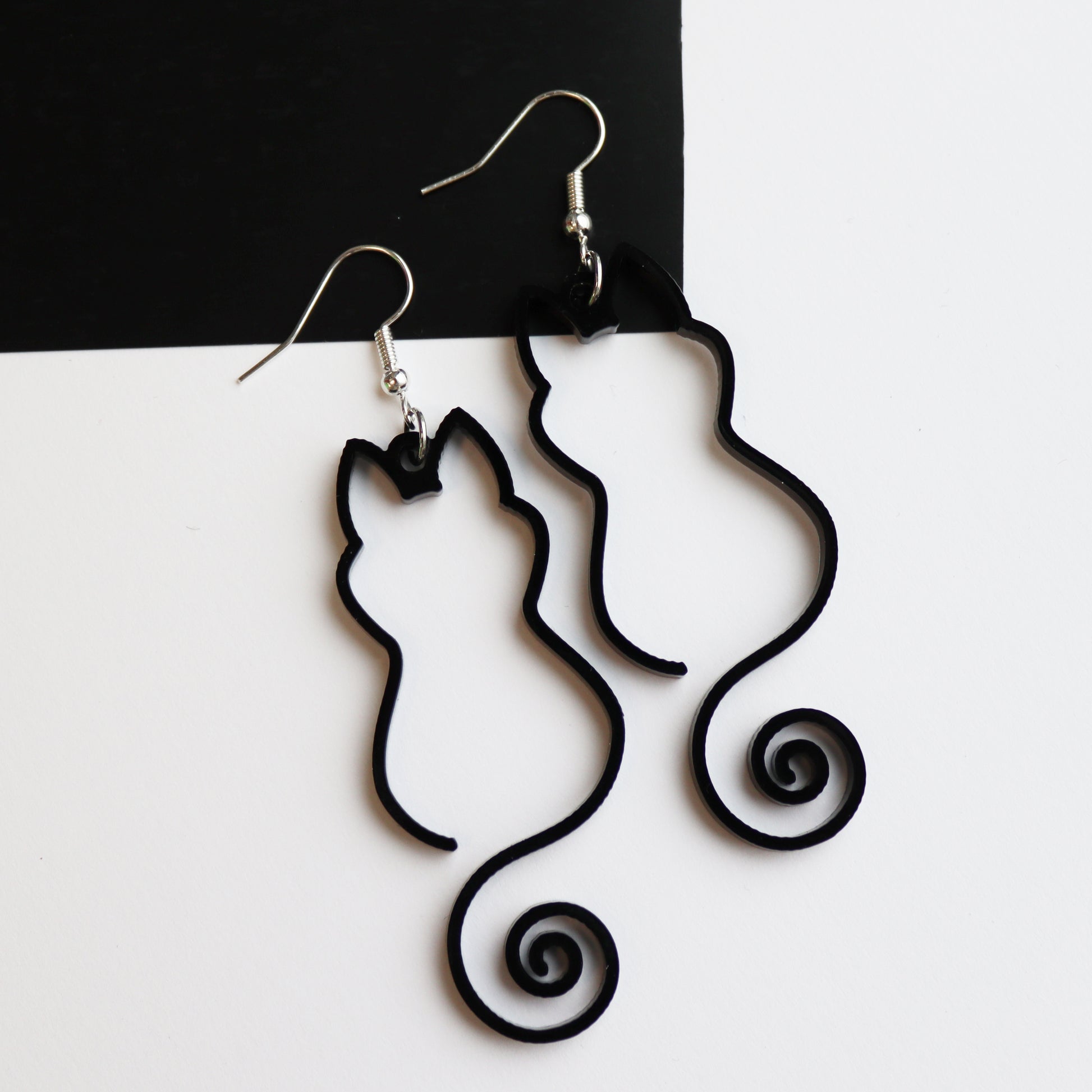 black cat outline pair of earrings acrylic outline cat earrings shown on white and black background close up