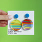 printed acrylic colourful handmade acrylic earrings on a turquoise background with circle