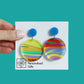 printed acrylic colourful mismatch earrings that have a round blue acrylic stud top and hanging printed acrylic circle hanging on a turquoise