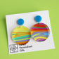 printed acrylic colourful mismatch earrings that have a round blue acrylic stud top and hanging printed acrylic circle hanging on a white card background
