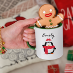 Personalised penguin Christmas mug with a name, set among festive decorations