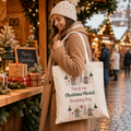 Cotton tote bag reading 'This is my Christmas Market Shopping Bag' with festive houses and trees, held at a market
