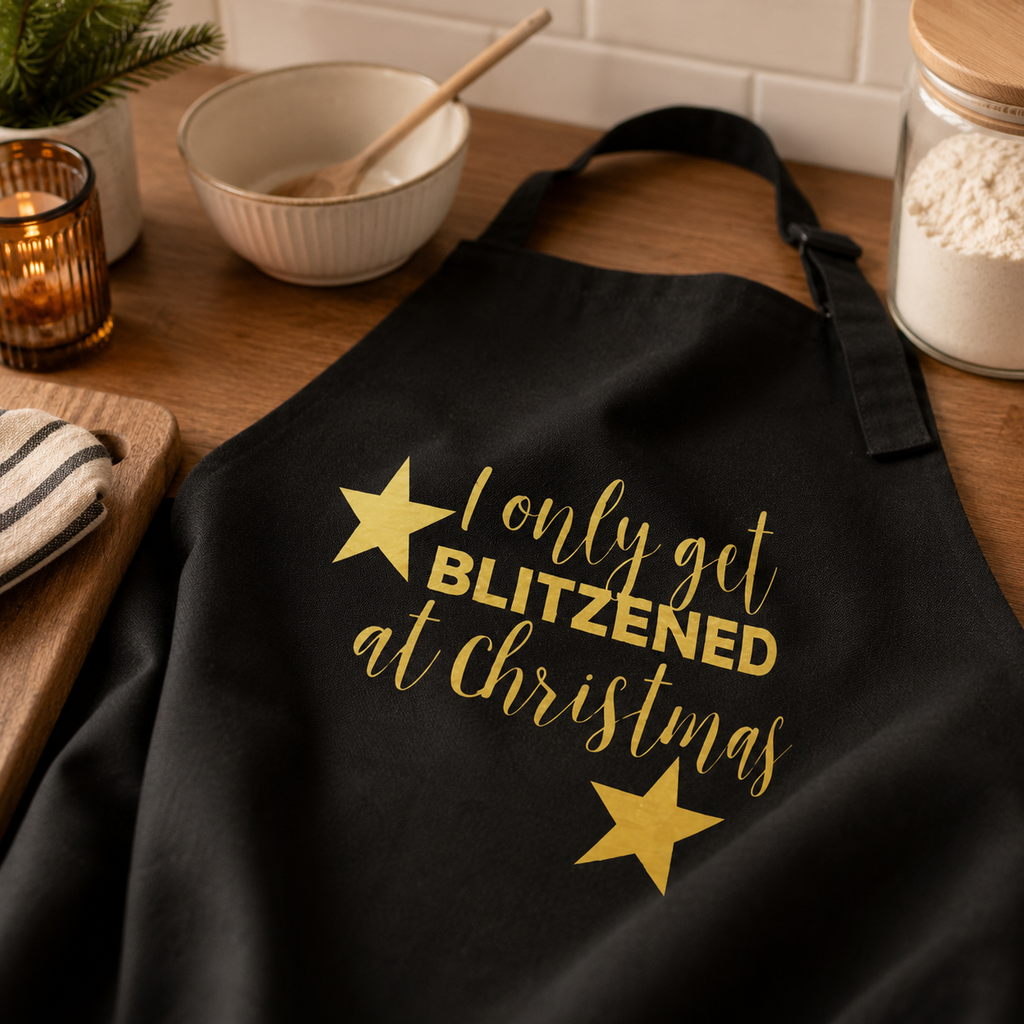 Black Christmas apron printed with 'I Only Get Blitzened at Christmas' in gold stars
