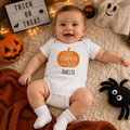 Baby wearing a white baby grow reading 'Cutest Pumpkin in the Patch' personalised with the name 'Amelia'