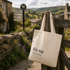 Cotton tote bag printed with an 'Ey up' dictionary definition, on a country gate in the Dales