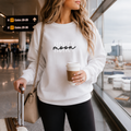 White honeymoon sweatshirt with 'Honeymoon' script, worn by a woman at an airport
