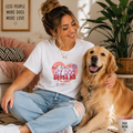 White t-shirt reading 'At least my dog loves me' with a heart and bone design, worn next to a dog