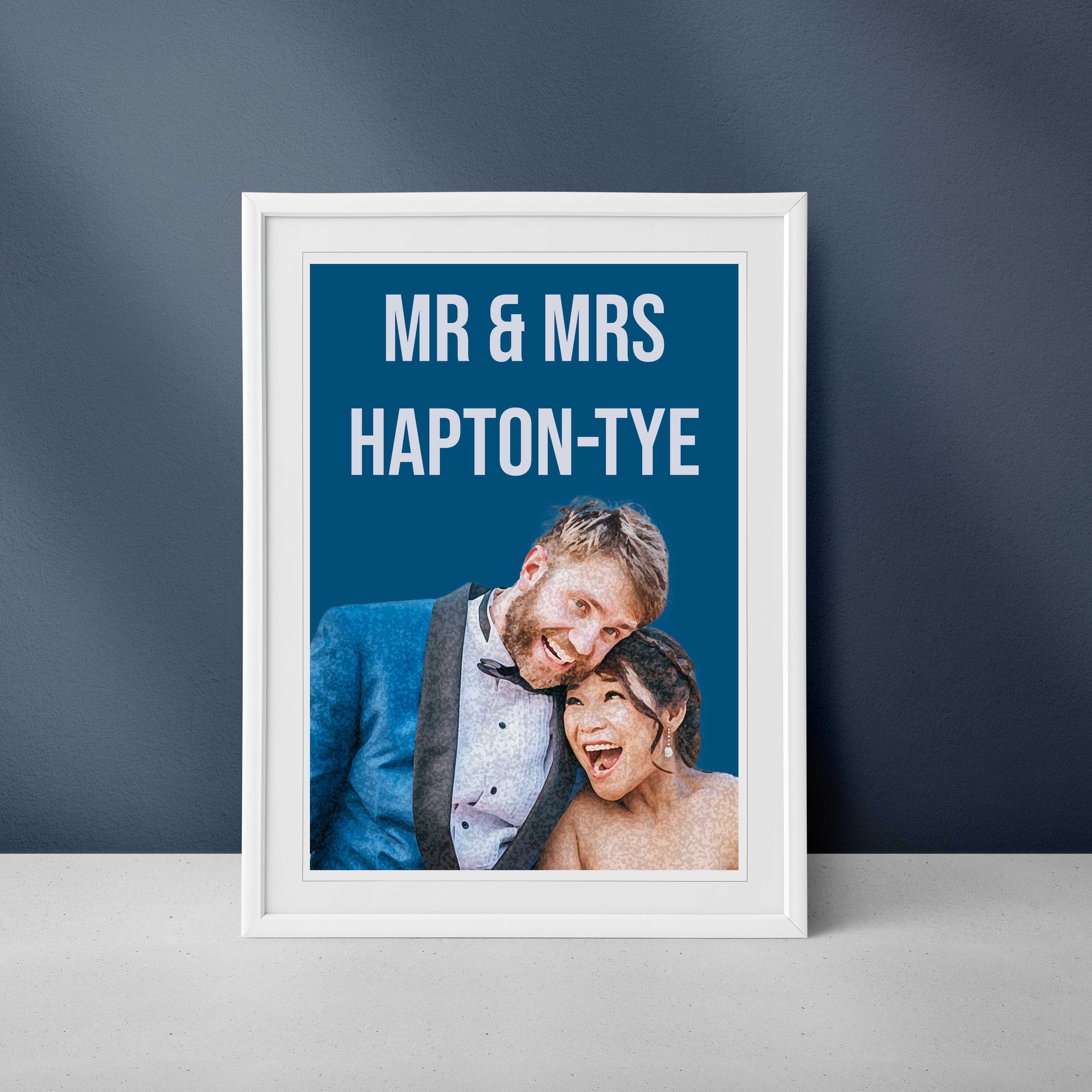 A framed wedding print featuring a couple, with the text 'MR & MRS HAPTON-TYE' at the top, displayed against a blue background.
