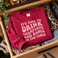 Burgundy champagne and dance slogan sweatshirt folded in an open drawer beside sequin fabric and leopard print, styled as a wardrobe flat lay.