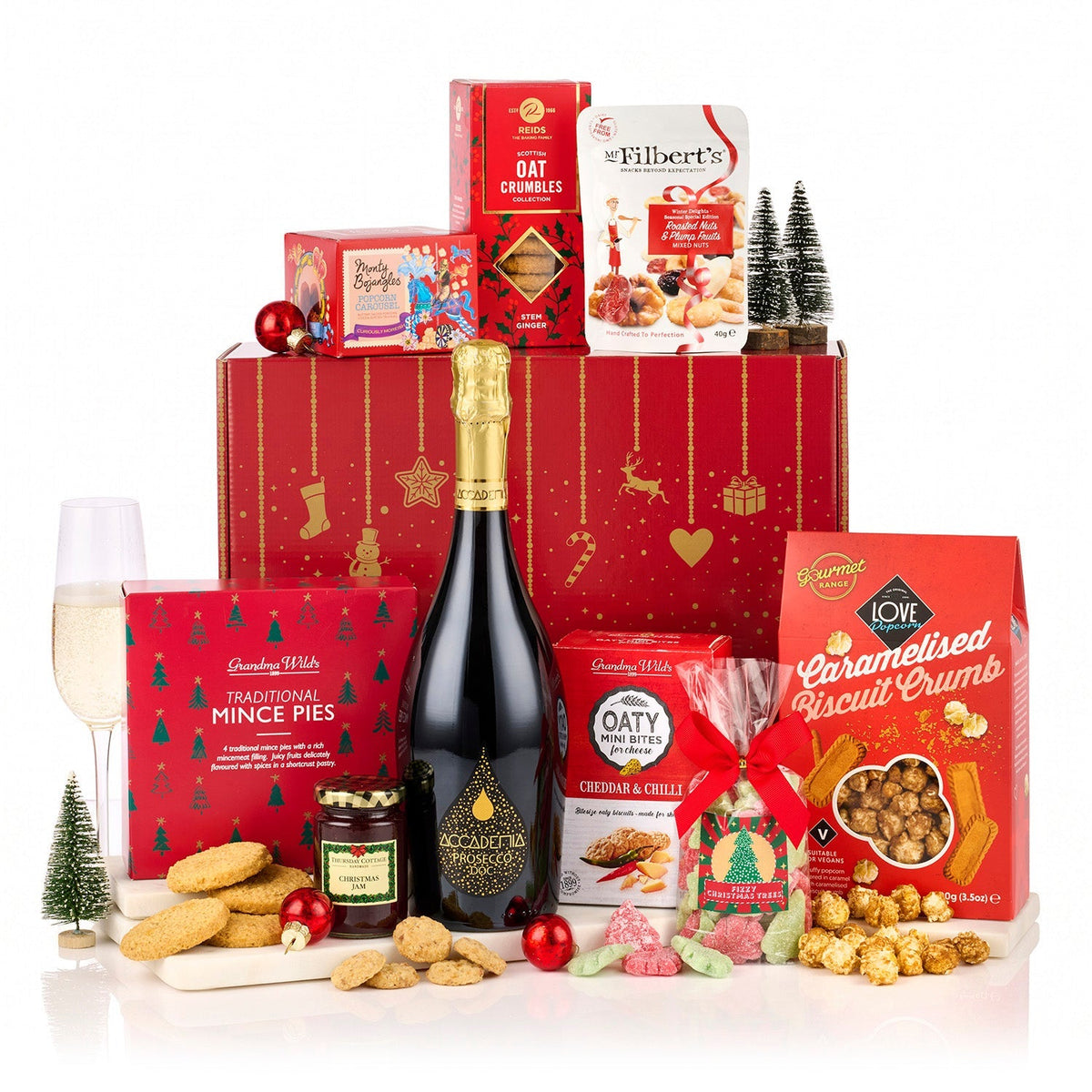 The Redsleeves Hamper with Prosecco, featuring Accademia Prosecco, mince pies, popcorn and jam by a red Christmas gift box