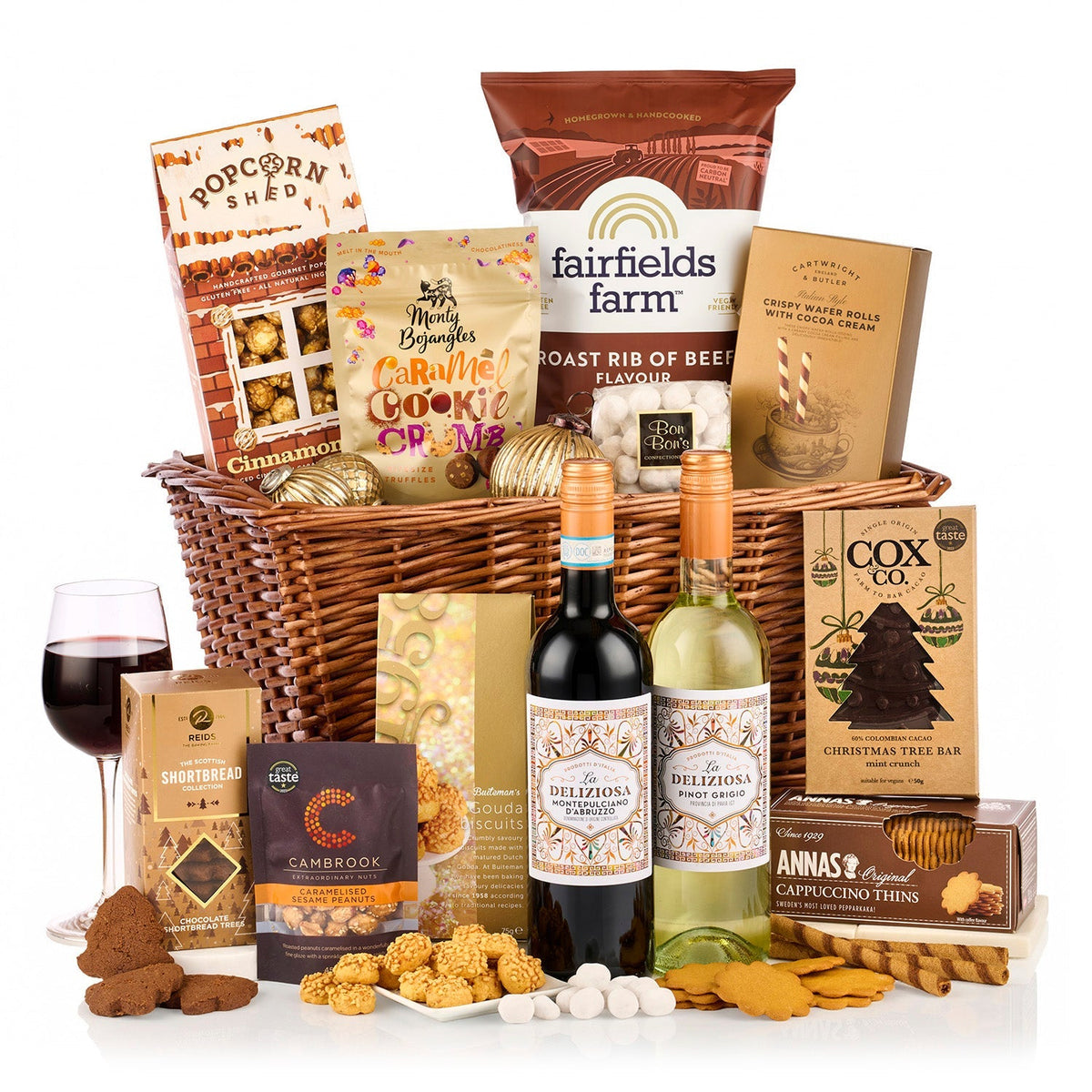 A Cosy Christmas Hamper with La Deliziosa red and white wine, popcorn, crisps, wafer rolls and shortbread in a wicker basket