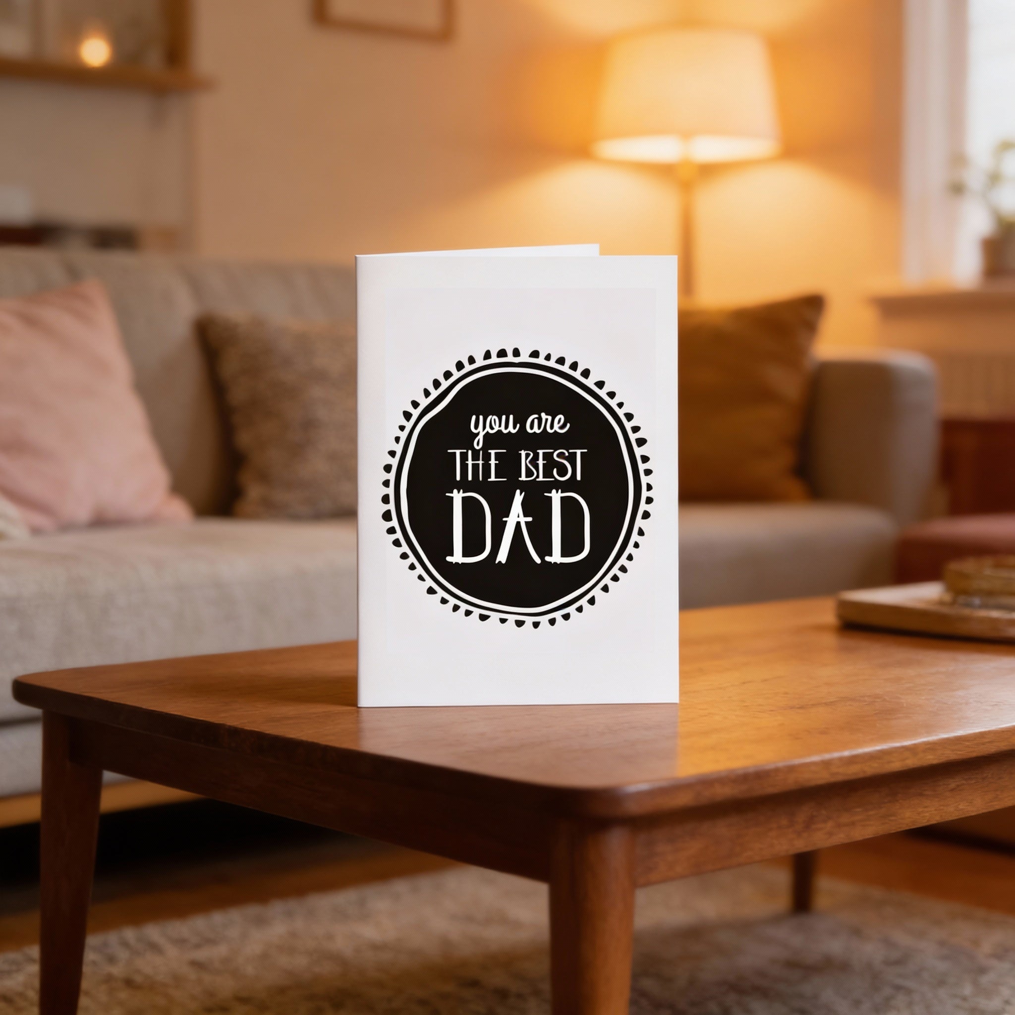 Card with 'You are the best Dad' text on a wooden table in a cozy living room.