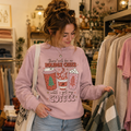 Woman browsing a boutique rail wearing a pink Holiday Cheer Until I Get My Coffee Christmas sweatshirt
