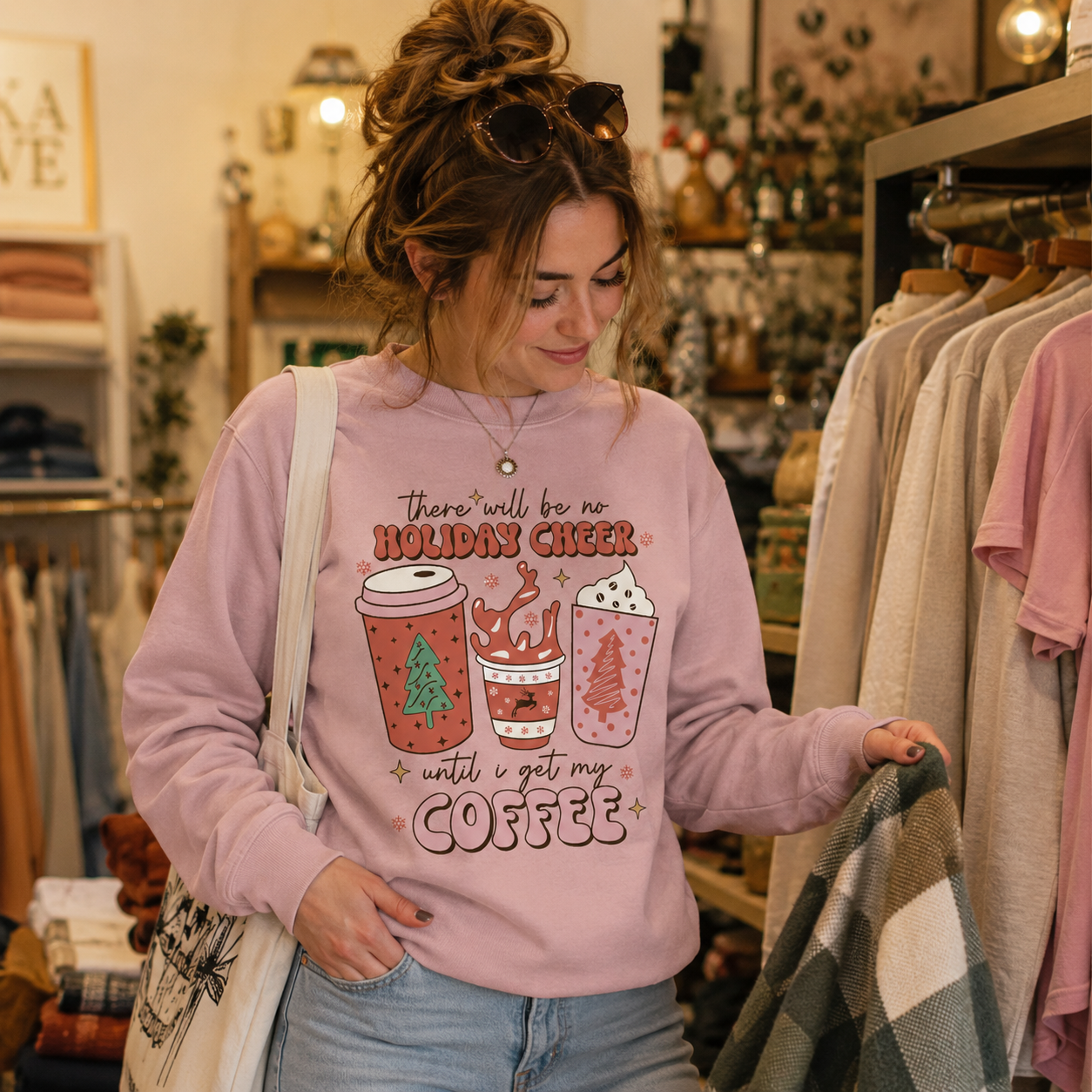 Woman browsing a boutique rail wearing a pink Holiday Cheer Until I Get My Coffee Christmas sweatshirt