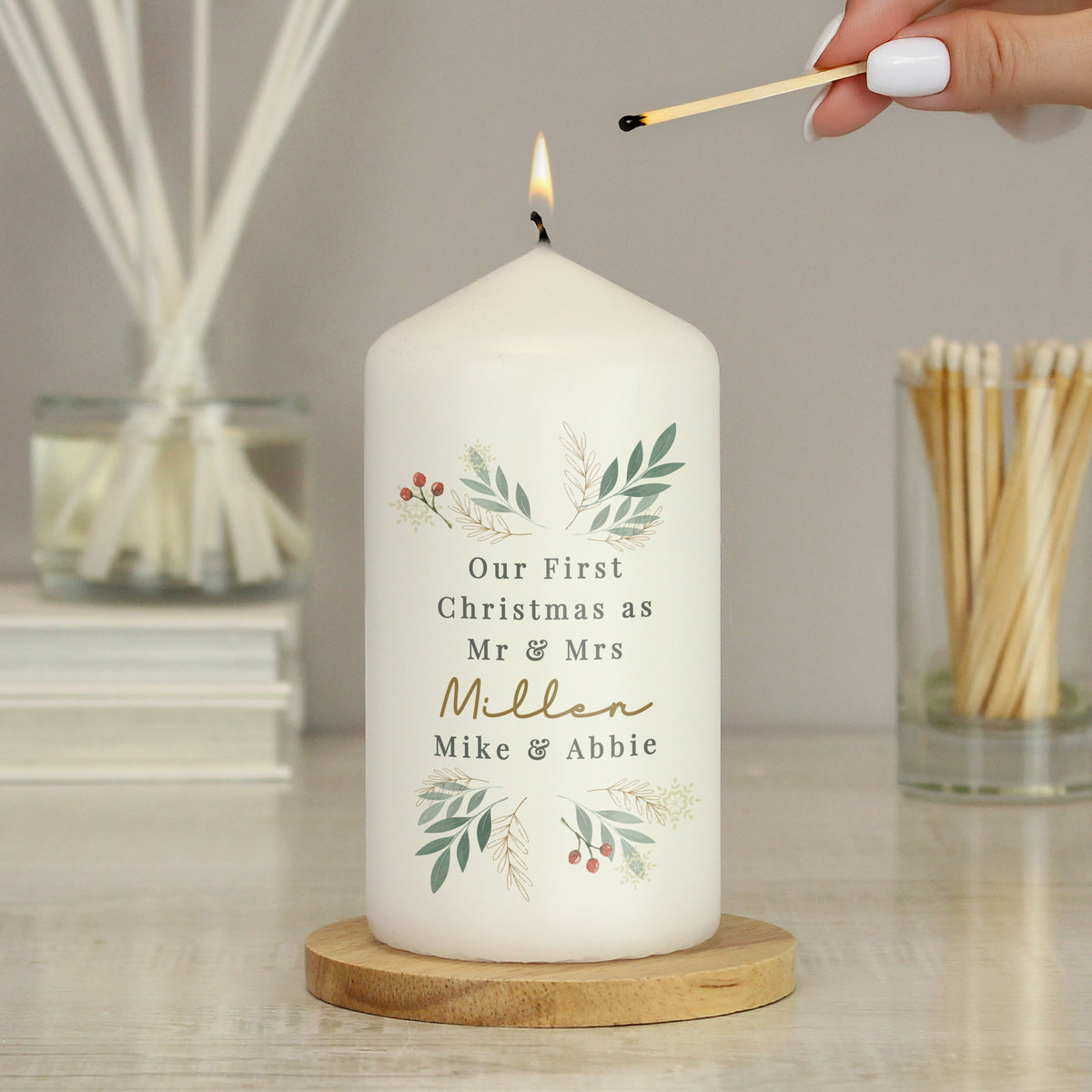 Personalised Christmas Foliage Pillar Candle lit on a wooden table