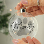 Personalised paw print glass Christmas bauble glowing on a lit tree