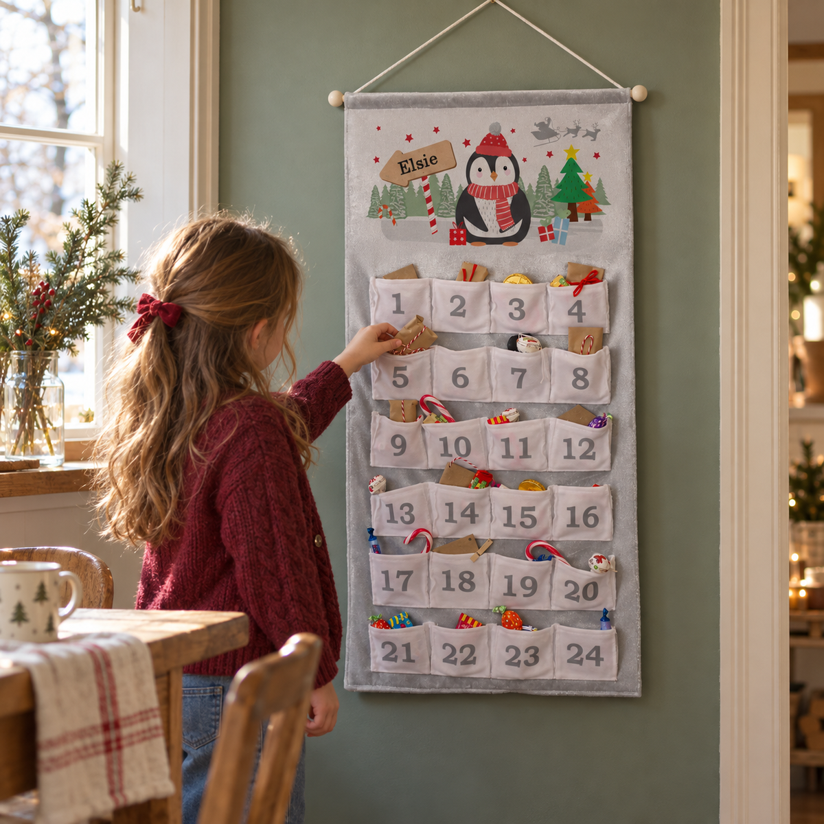 Girl opening the Personalised Christmas Penguin Advent Calendar on a green wall