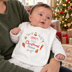Baby wearing a personalised First Christmas Dinner bib by the Christmas tree