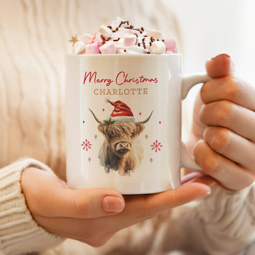 Personalised Christmas Highland cow mug in a Santa hat, topped with hot chocolate