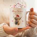 Personalised Christmas Highland cow mug in a Santa hat, topped with hot chocolate