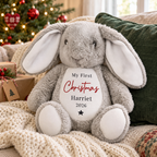 Personalised My First Christmas grey bunny soft toy on a sofa by the Christmas tree