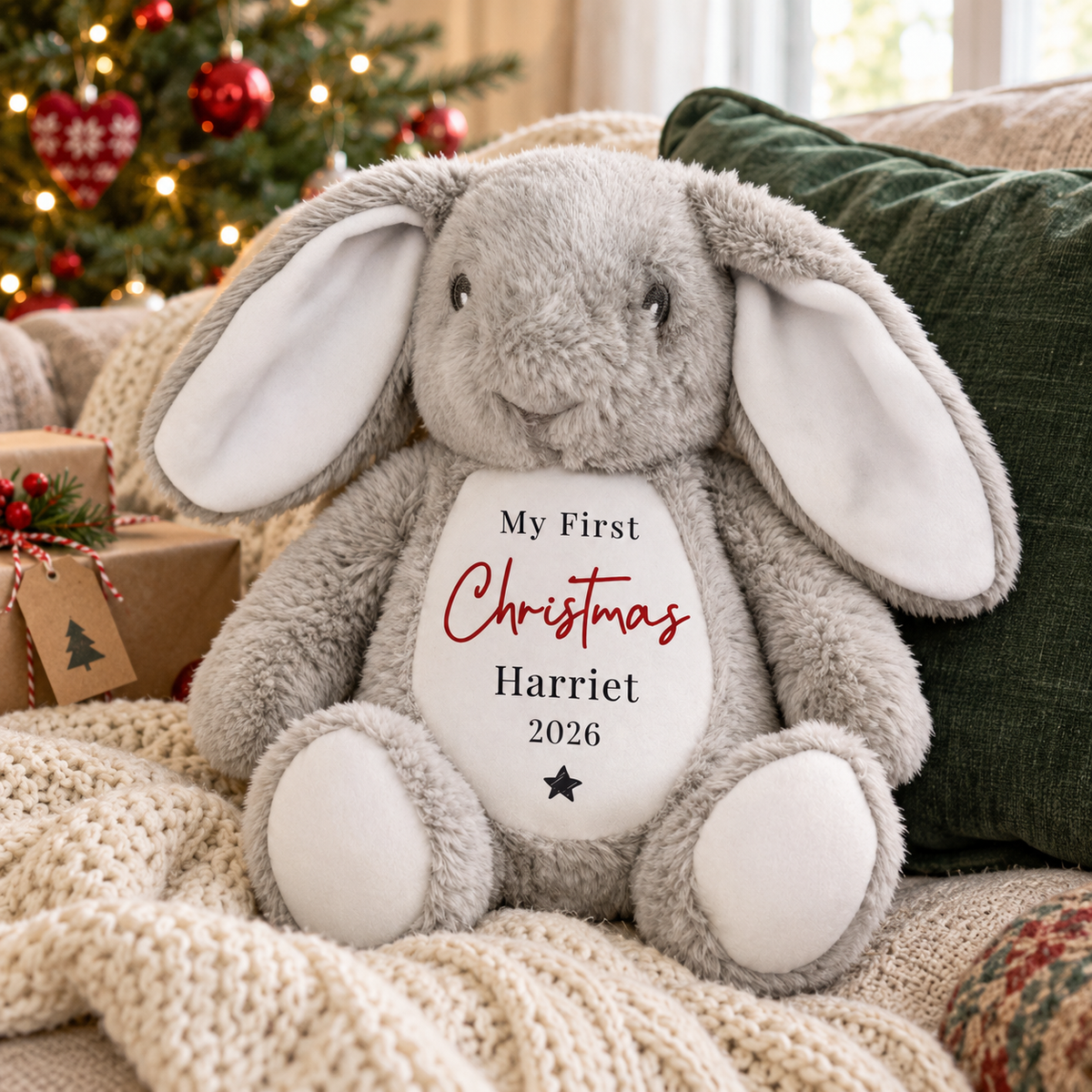 Personalised My First Christmas grey bunny soft toy on a sofa by the Christmas tree
