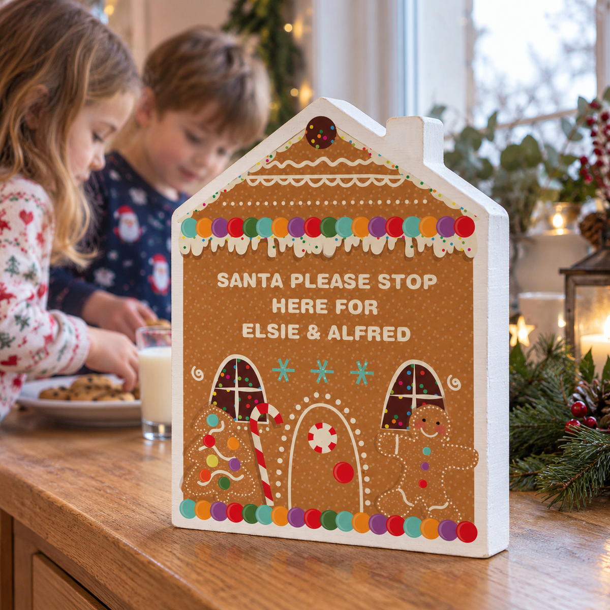 Personalised Gingerbread House Christmas Ornament on a windowsill with children behind