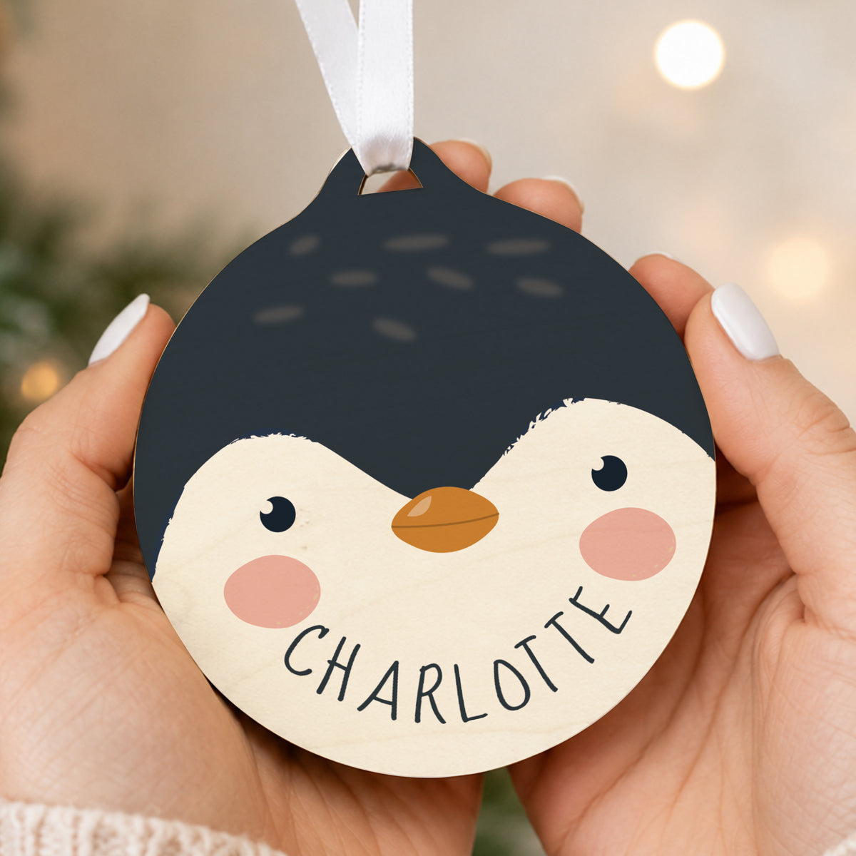 Personalised Penguin Wooden Bauble hanging on a Christmas tree