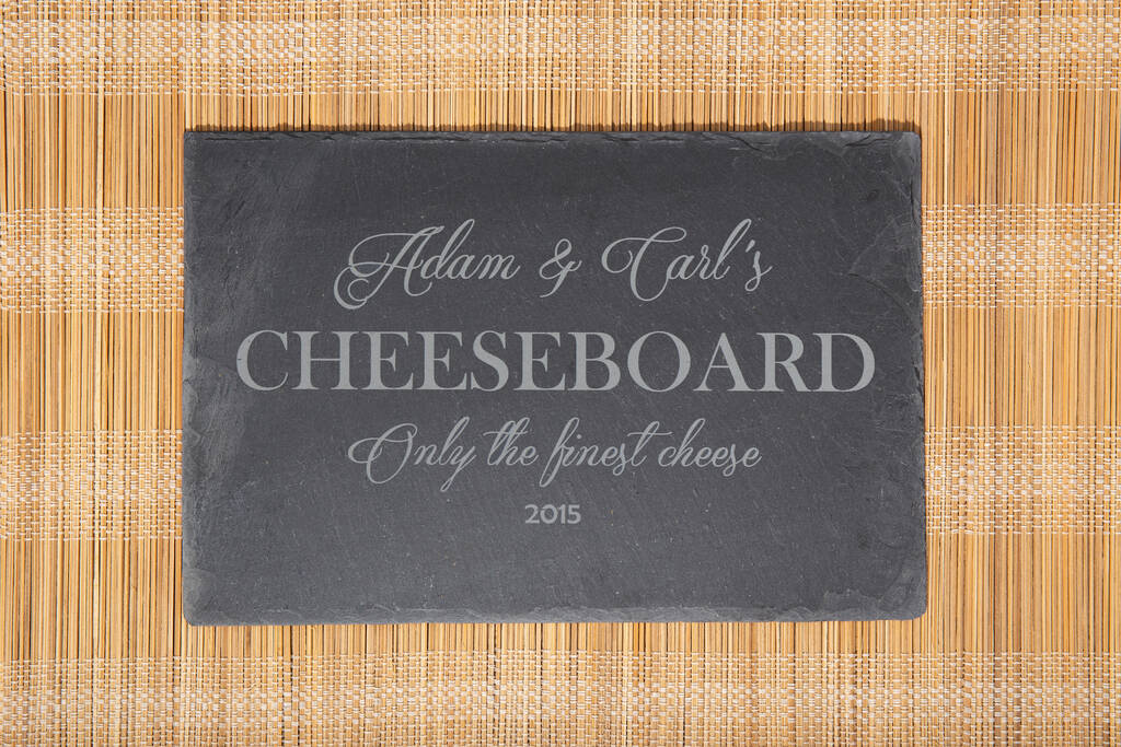 Personalised rectangular slate serving board with engraved wording and a selection of cheese and accompaniments.
