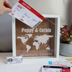 A personalized black shadow box with an acrylic front, displaying travel tickets and bearing the text 'Adventure Tickets'.