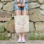 A person holding a beige tote bag with a heart pattern and a personalized message that reads 'Thank you for being such an inspiring teacher. The world needs more educators like you.