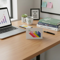Laptop on a desk with a 'Yes, Women Can' card, books, and a mug.