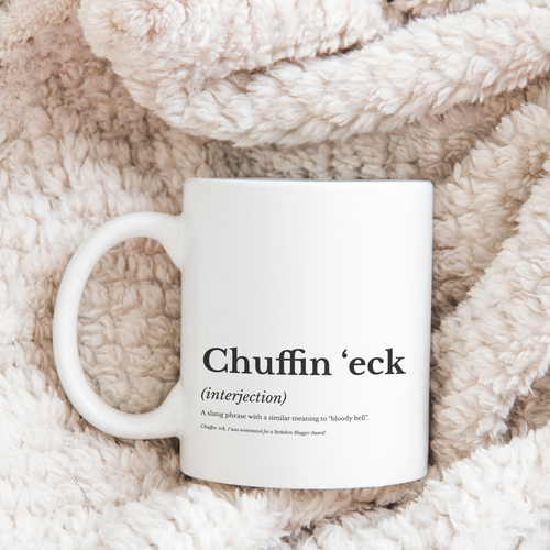 White mug printed with a 'Chuffin 'eck' Yorkshire dictionary definition, on a soft blanket