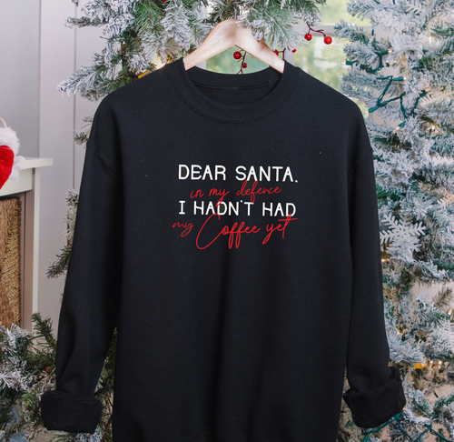 Coffee lover Christmas jumper with 'Dear Santa' coffee slogan, shown against a festive tree backdrop