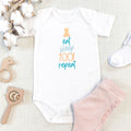 White baby grow with teddy design reading 'Eat sleep poop repeat'