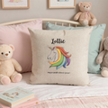 Personalised unicorn cushion cover with rainbow mane and the name 'Lottie' on a child's bed with teddies