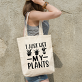 Black cotton tote bag printed with 'I Just Wet My Plants' slogan and potted plant design