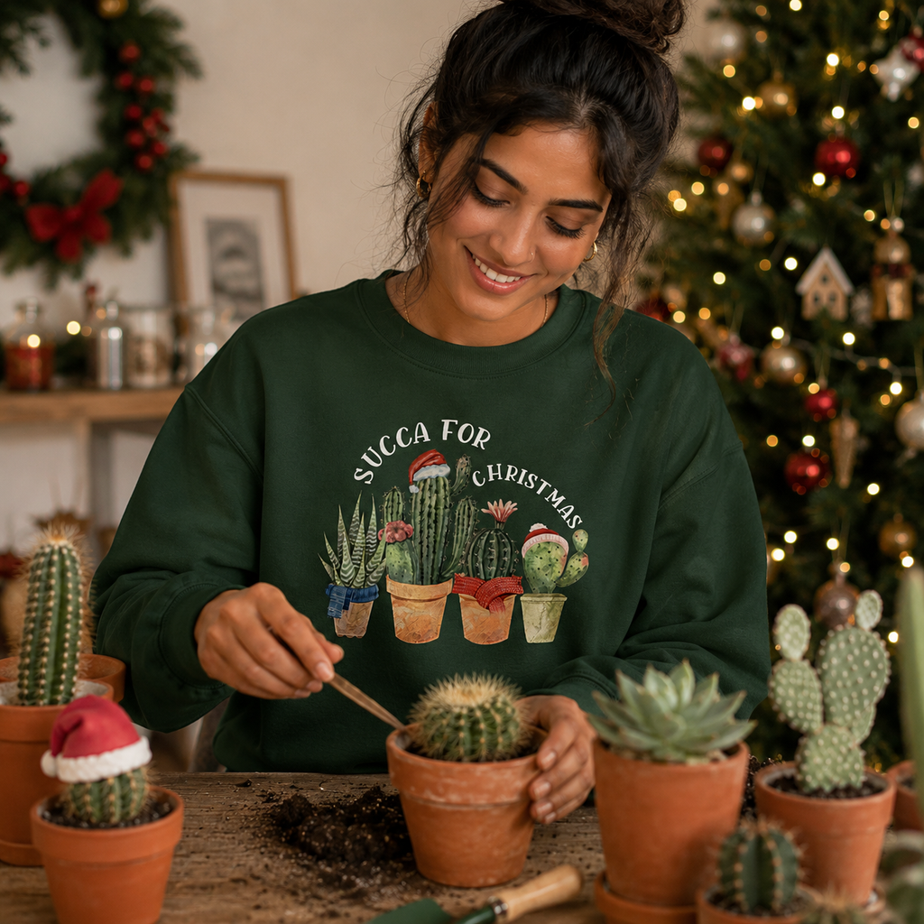 Woman potting a cactus, wearing a green Succa For Christmas succulent jumper, indoors with a Christmas tree.