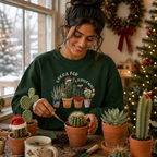 Woman by a window potting plants, wearing a green Succa For Christmas succulent jumper.