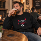 Man wearing a black Permanently On The Naughty List Christmas jumper, holding a pint in a pub.