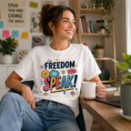 Woman wearing a white Freedom To Speak t-shirt, holding a mug at a desk with a bookshelf and plants.