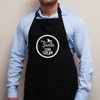'Dear Santa I Can Explain' Christmas apron in black with a white sleigh badge slogan