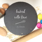 Engraved black slate cake plate featuring personalised text, surrounded by baking essentials.