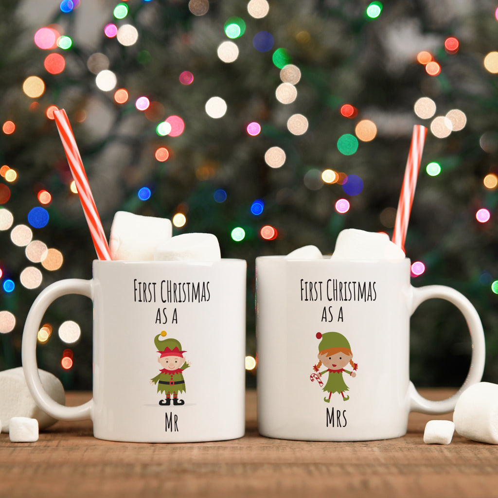 Two white ceramic mugs with a Christmas design, one labeled 'Mr' and the other labeled 'Mrs', with candy canes and Christmas lights in the background.