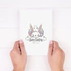 A greeting card with a colorful illustration of a bunny with a 'Happy Easter' message, held between fingers.