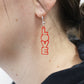 LOVE red acrylic laser cut earrings than dangle in this image shown being worn for a size reference