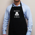 A person wearing a black apron with a 'Merry Force Be With You' Christmas design, featuring a Darth Vader helmet graphic.