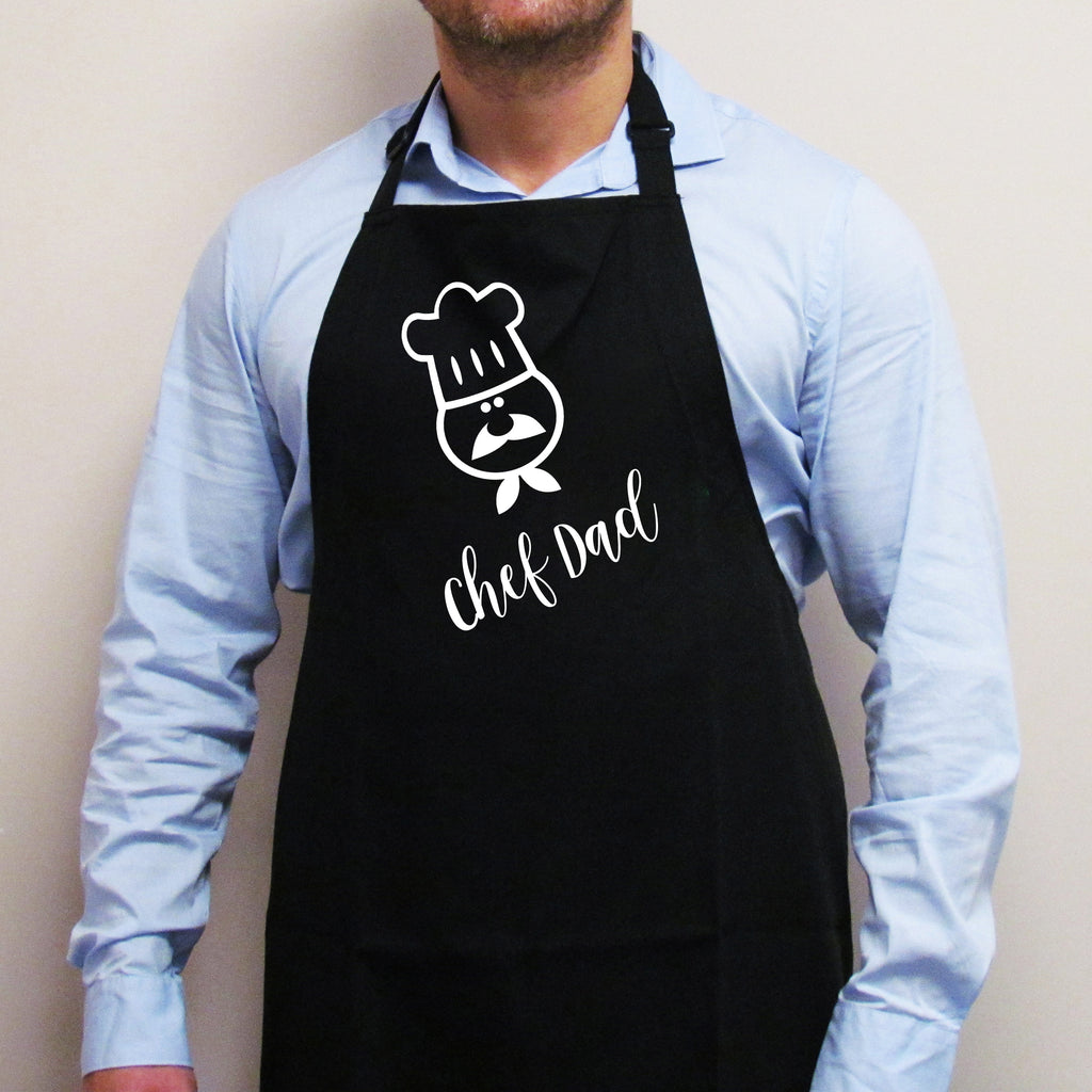 A person wearing a black apron with the text 'CHEF DAD' on the front.