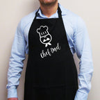 A person wearing a black apron with the text 'CHEF DAD' on the front.